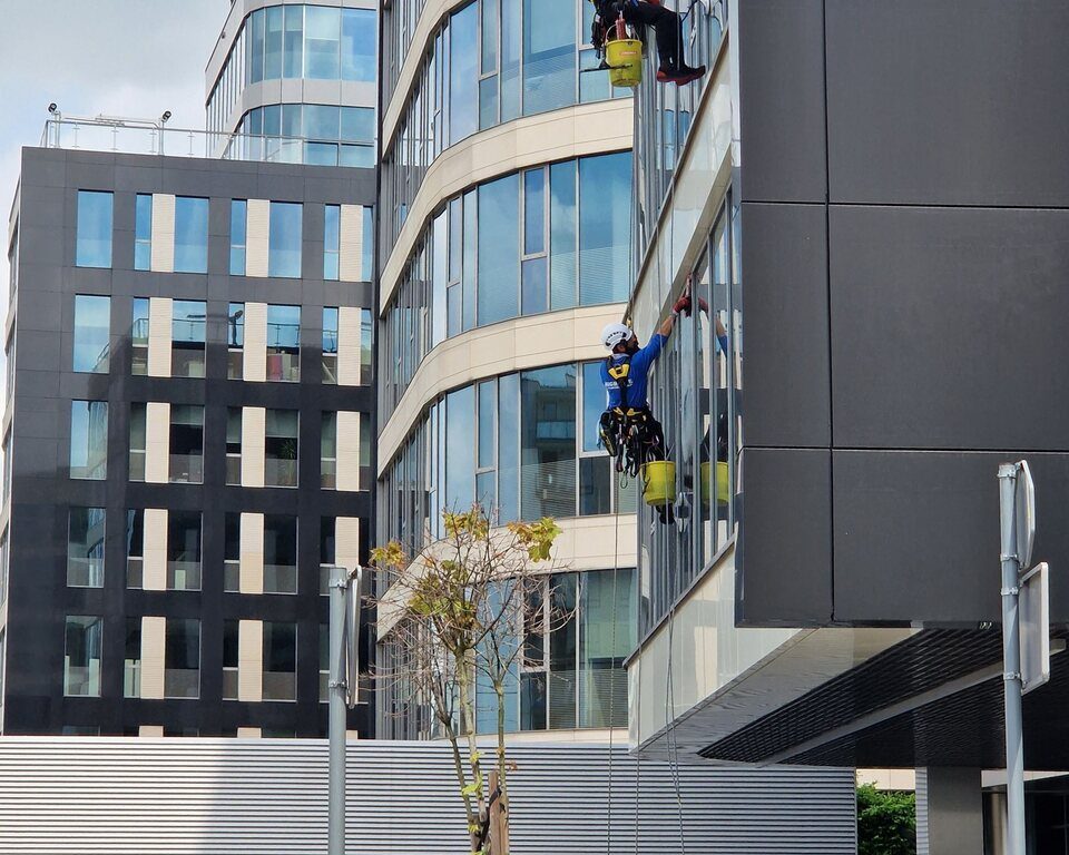 Professional cleaners maintaining the glass facade of a commercial office building
